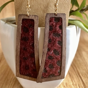 Detalle de pendientes rectangulares de madera con textura de leopardo y ganchos dorados