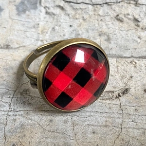 Makroaufnahme: Verstellbarer Bronzering mit rot-schwarz karierter Glaskuppel im Vintage-Stil