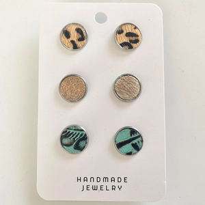 Close-up of three pairs of leopard print, gold glitter, and blue feather stud earrings