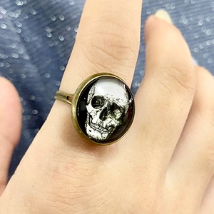 Vintage Bronze-Ring mit Totenkopf und Glaskuppel auf blau glitzerndem Hintergrund