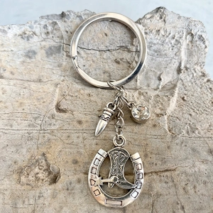 Western style silver horseshoe and cowboy boot keychain with rhinestone on stone surface