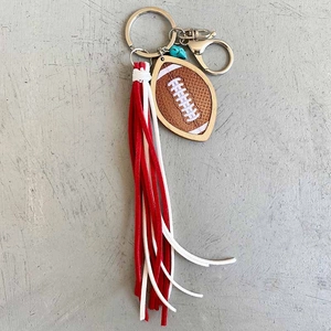 Porte-clés rugby avec pompon rouge et blanc et perle turquoise sur fond gris neutre