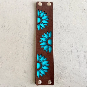 Détail d'un bracelet en cuir bohème avec tournesols turquoise et boutons pressions