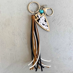 Détail d'un porte-clés à franges avec pendentif flèche motif vache et perle turquoise
