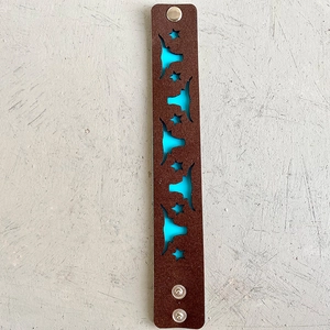 Détail de tête de bœuf et étoiles sur bracelet en cuir marron avec doublure bleue