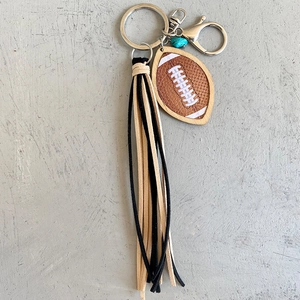 Vue détaillée du porte-clés football avec longues franges en daim noir et jaune et perle