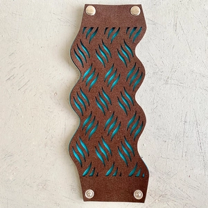 Détail d'un bracelet en cuir tournesol avec doublure bleue et motifs découpés au laser