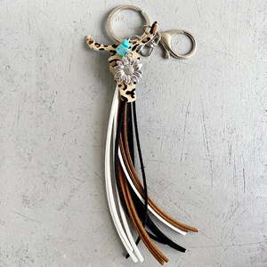 Détail du porte-clés tête de taureau léopard avec perle turquoise et franges bohèmes