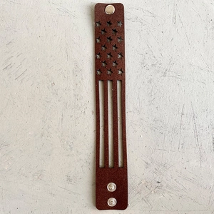 Détail du bracelet en cuir marron avec motif drapeau américain découpé au laser