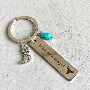 Detail of western keychain with cowboy boot charm, turquoise bead, and engraved metal tag