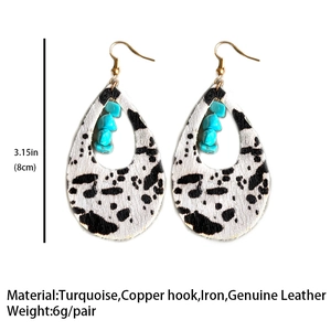Detailed view of teardrop cow print earrings with turquoise stone and golden hooks