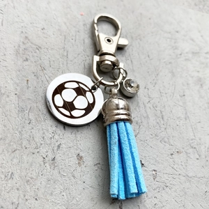 Porte-clés ballon de football avec pompon bleu clair et cristal sur fond de pierre