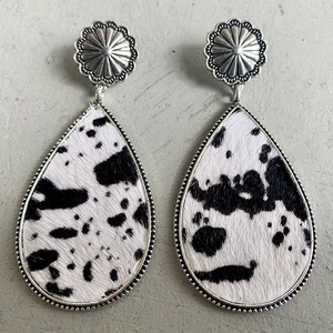Close-up of teardrop leather earrings with cow print pony hair and floral metal studs