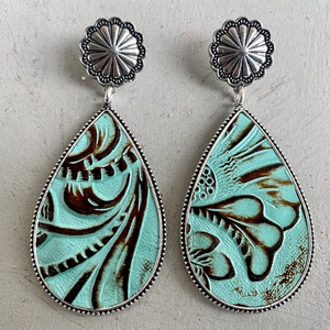 Vista de detalle de pendientes de cuero turquesa con grabado floral y pasadores de plata vieja