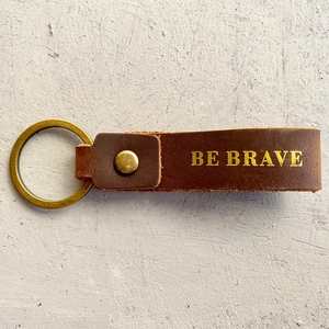 Detail of brown crazy horse leather keychain with Be Brave engraving and bronze ring