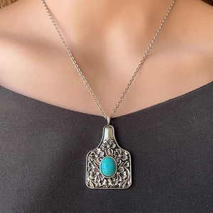 Vue détaillée du pendentif turquoise style western avec gravures florales argentées
