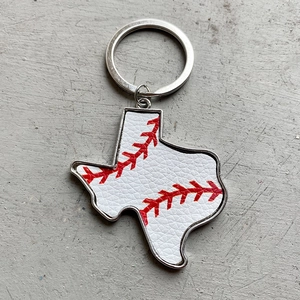 Macro detail of Texas state map keychain with baseball leather texture and silver edges
