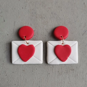 Detail van handgemaakte envelop-oorbellen met rood hart van matte polymeerklei