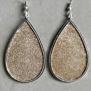 Détail de boucles d'oreilles en argent avec paillettes dorées et bordure perlée