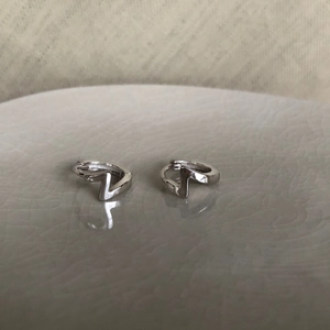 Détail macro de boucles d'oreilles éclair géométriques argentées sur céramique