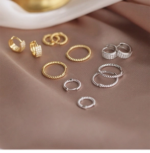 Detalle de pendientes de aro trenzados en oro y plata con pavé de circón sobre terciopelo