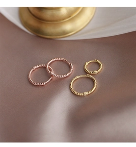 Detalle de pendientes de aro con diseño de cuerda trenzada en oro y oro rosa