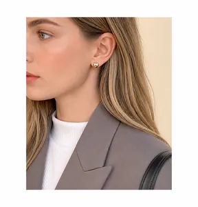 Primer plano de un pendiente de corazón de oro pulido en una modelo de estilo minimalista