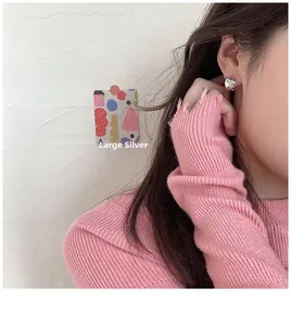 Primer plano de pendientes de corazón plateados grandes usados por una modelo de moda
