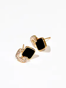 Primer plano de pendientes dorados con cuadrado negro y forma de C con cristales brillantes