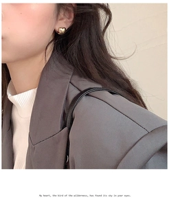 Primer plano de elegantes pendientes de corazón dorados usados por una modelo con traje formal