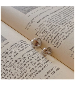 Primer plano detallado de pendientes de botón de corazón 3D en páginas de libros