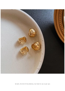 Detalle de pendientes de aro con forma de corazón dorado 3D sobre plato de cerámica