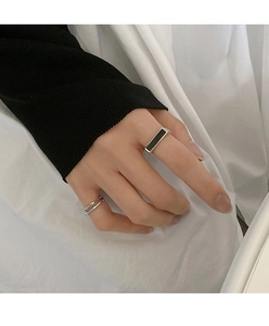 Anillo abierto de plata con incrustación negra y banda a capas en mano de modelo