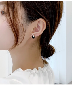Primer plano de elegantes pendientes cuadrados en esmalte negro y oro usados por una modelo