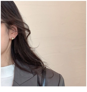 Primer plano de pendientes de corazón dorados en una modelo con estilo minimalista