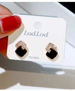 Primer plano de pendientes cuadrados de esmalte negro con marco de oro rosa y cristales
