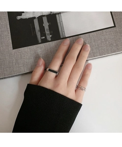 Primer plano de anillo minimalista plateado con esmalte negro y banda ondulada