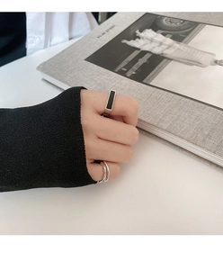 Detalle del anillo de esmalte negro S925 y banda ondulada en la mano de la modelo