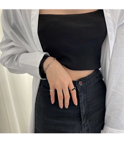 Conjunto pulsera plateada y anillos con incrustación negra en tela blanca