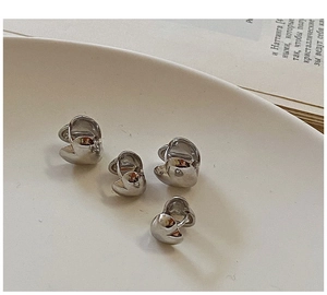 Primer plano de pendientes de aro plateados con forma de corazón en un plato cerámico