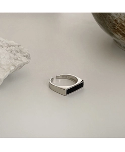 Primer plano de anillo de plata S925 con esmalte rectangular negro sobre fondo de piedra