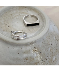Detalle macro de anillos ajustables de plata S925 con incrustación negra sobre cerámica