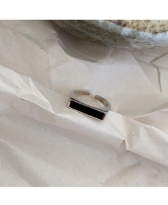 Primer plano de anillo de plata S925 con esmalte negro rectangular en fondo texturizado