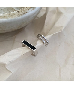 Detalle de anillos de plata con incrustación rectangular negra y textura metálica fluida