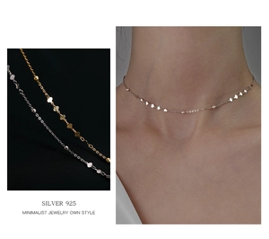 Dettaglio di un girocollo minimalista in argento 925 con cuori e perline su modella e sfondo nero
