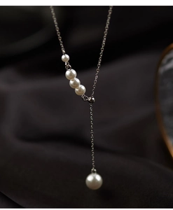 Détail du collier en Y argenté orné de perles blanches élégantes sur de la soie