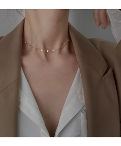 Primo piano di una collana choker dorata con perline delicate su una modella