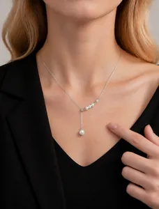 Détail d'un collier de perles argenté en forme de Y porté par un mannequin