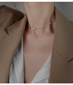 Primo piano di una collana choker dorata con ciondoli a cuore sulla clavicola