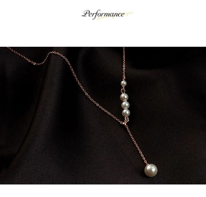 Gros plan du collier en Y en or rose avec cinq perles blanches sur de la soie foncée